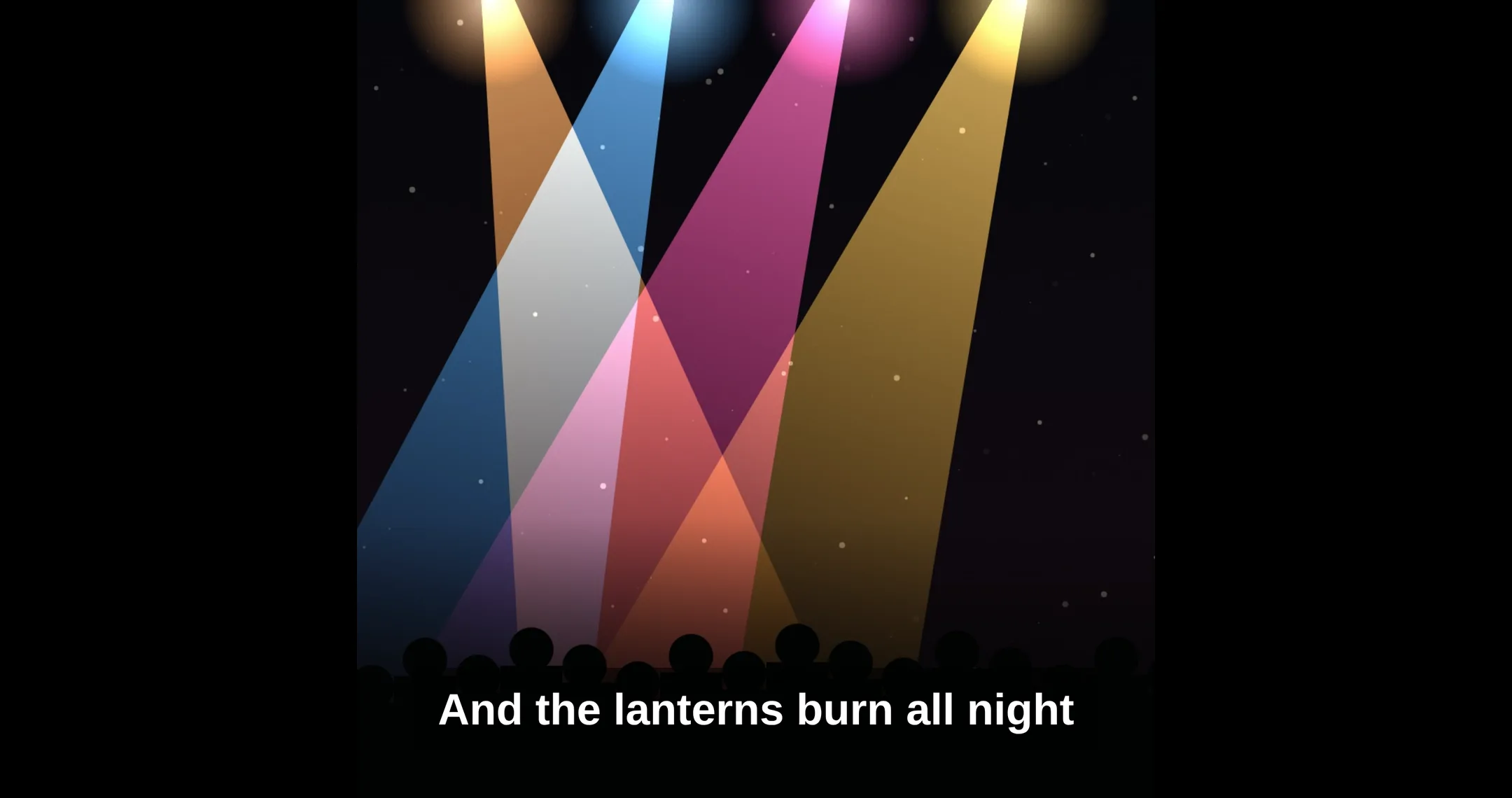 The stage screen as the audience sees it: a song's square video of coloured stage lights, centred on black, with the subtitle 'And the lanterns burn all night' across the bottom.